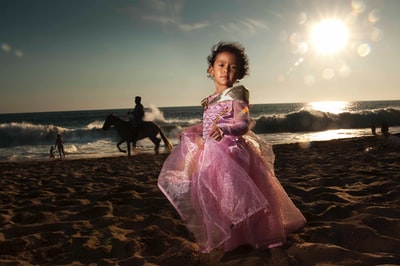 白天，穿着紫色裙子的女人站在海滩上
